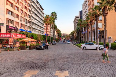 Gün batımında kafeleri ve palmiye ağaçları olan canlı bir şehir caddesi. 4 Ağustos 2025, İzmir Türkiye.