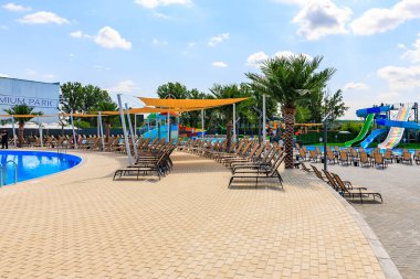 Havuzu ve bir sürü şezlongu olan bir plaj. Sandalyeler yayılmış ve birkaç şemsiye var. 8 Haziran 2024 Balti Moldova