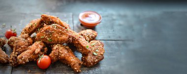 Susamlı fırında tavuk kanadı. Ketçap ve acı sos. Metin için boş alan. Ahşap arka plan. Lezzetli kızarmış tavuk kanatları..