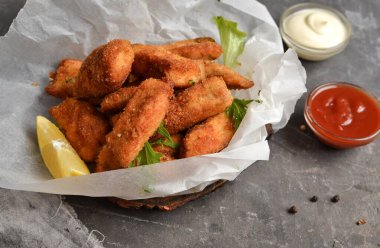 Ev yapımı tavuk nugget. Beyaz parşömen üzerinde külçeler. Ketçap ve mayonez. Kopyalama. Gri arkaplan.