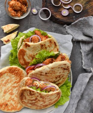 Kızarmış tavuk ve sebzeli lavaş salatası. Tavuk nuggetlı Pita, domates, kırmızı soğan ve marul ve sos. Sağlıklı fast food. Üst Manzara. Koyu arkaplan.