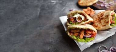 Kızarmış tavuk ve sebzeli lavaş salatası. Tavuk nuggetlı Pita, domates, kırmızı soğan ve marul ve sos. Sağlıklı fast food. Karanlık arka plan. Kopyalama alanı