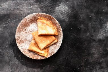 Güzel kahvaltı. Karamelli, çikolatalı ve muzlu ince krepler. Karanlık arka plan. Üst Manzara. Kopyalama alanı