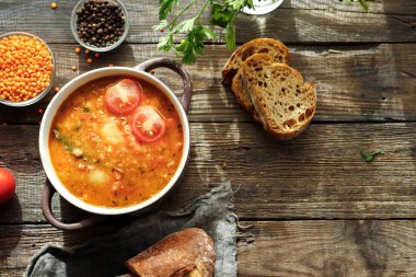 Kırmızı mercimek çorbası ve malzemeler. Ahşap arka plan, üst manzara. Mercimek ve sebzelerden yapılan geleneksel baharatlı çorba. Sağlıklı vejetaryen yemekleri
