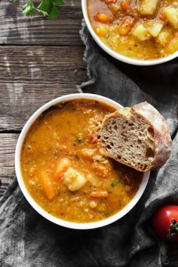 Kırmızı mercimek çorbası ve malzemeler. Ahşap arka plan, üst manzara. Mercimek ve sebzelerden yapılan geleneksel baharatlı çorba. Sağlıklı vejetaryen yemekleri