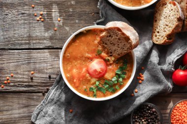 Kırmızı mercimek çorbası ve malzemeler. Ahşap arka plan, üst manzara. Mercimek ve sebzelerden yapılan geleneksel baharatlı çorba. Sağlıklı vejetaryen yemekleri