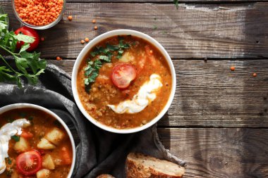 Kırmızı mercimek çorbası ve malzemeler. Ahşap arka plan, üst manzara. Mercimek ve sebzelerden yapılan geleneksel baharatlı çorba. Sağlıklı vejetaryen yemekleri