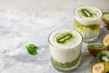 Bardakta kivi ve yoğurt. Meyve ve meyve püresi. Kivi ve muzlu milkshake. Sağlıklı beslenme. Hafif arkaplan. Uzayı kopyala Vejetaryen yemeği