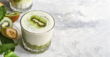 Bardakta kivi ve yoğurt. Meyve ve meyve püresi. Kivi ve muzlu milkshake. Sağlıklı beslenme. Hafif arkaplan. Boşluğu kopyala.