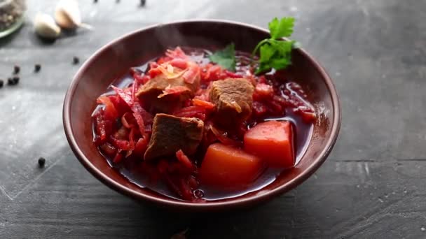 Röd borsch med grönsaker och kött i en lertallrik. Ånga från varm tomatsoppa. Mörk bakgrund. Läcker hälsosam lunch. — Stockvideo