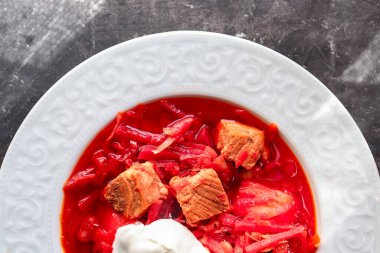 Red borsch with vegetables and meat in a white plate. Tomato soup. Dark background. Delicious healthy lunch. clipart