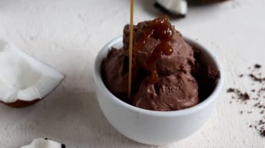 Karamelli hindistan cevizli çikolatalı dondurma. Dondurma karamel ya da çikolata sosuyla süslenir. Yavaş çekim..