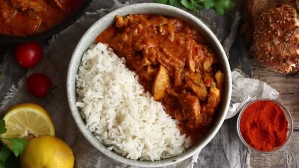 Curry tradicional e ingredientes. Tikka Masala pollo y arroz. Comida india. Vista superior. Copiar espacio. Fondo de madera. — Vídeo de stock