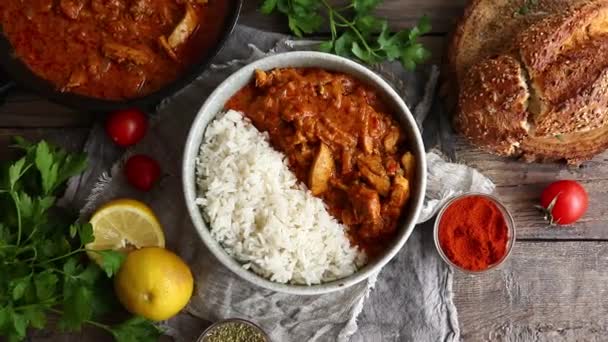 Curry traditionnel et ingrédients. Tikka Masala poulet et riz. De la nourriture indienne. Vue de dessus. Espace de copie. Fond en bois. — Video