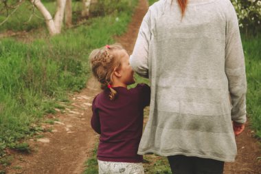 Anne ve kızı el ele tutuşuyorlar. Arkadan bak. Kız kardeşler el ele tutuşarak yürür. Doğadaki bir çocuğun portresi. Uzayı kopyala Güzel sarışın kız 4 yaşında..