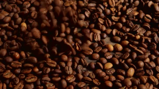 Geröstete Kaffeebohnen fallen auf eine Holzoberfläche. Zeitlupe. — Stockvideo