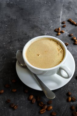 Kahve fincanı ve kahve çekirdekleri koyu beton arka planda. Uzayı kopyala Espresso ya da Amerikano..