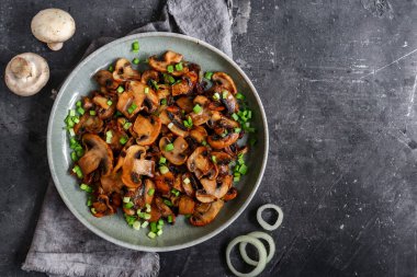 Kızarmış mantarlı ve soğanlı, ahşap arka planda, üst tarafta.