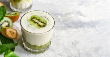 Bardakta kivi ve yoğurt. Meyve ve meyve püresi. Kivi ve muzlu milkshake. Sağlıklı beslenme. Hafif arkaplan. Uzayı kopyala Vejetaryen yemeği