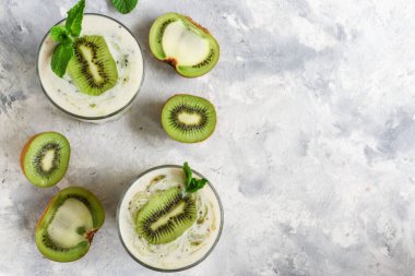 Bardakta kivi ve yoğurt. Meyve ve meyve püresi. Kivi ve muzlu milkshake. Sağlıklı beslenme. Hafif arkaplan. Boşluğu kopyala.