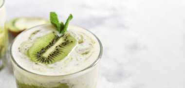 Bardakta kivi ve yoğurt. Meyve ve meyve püresi. Kivi ve muzlu milkshake. Sağlıklı beslenme. Hafif arkaplan. Boşluğu kopyala.