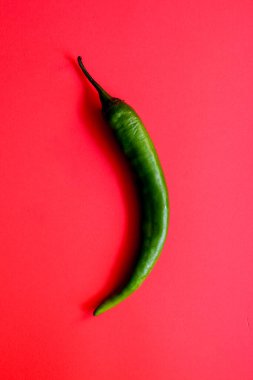 Kırmızı arkaplanda tek yeşil biber, kopyalama alanı ile yaratıcı minimalizm kavramı.