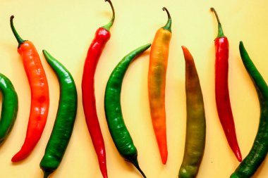 Sarı arka planda çok renkli kırmızı biber, fotokopi alanı ile yaratıcı minimalizm kavramı. Üst görünüm