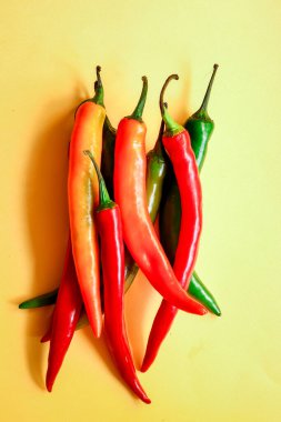 Sarı arka planda çok renkli kırmızı biber, fotokopi alanı ile yaratıcı minimalizm kavramı. Üst görünüm