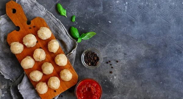 Rå köttbullar på en träskiva. Mörk bakgrund. Kopieringsutrymme. Matlagning kyckling köttbullar. — Stockfoto