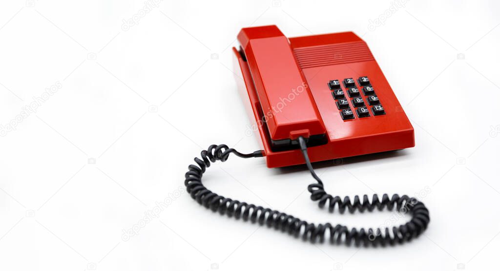 Desktop telephone from the 80's and red color isolated on a white background. Space for text. Communication concept.