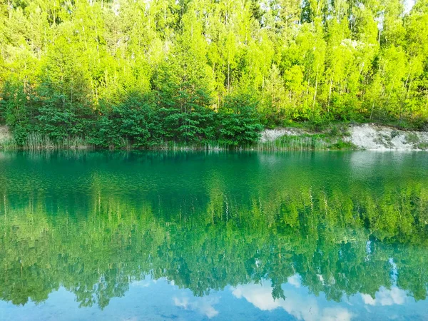 A beautiful river with turquoise, clear water. Reflection of trees on clear water. View of the river from the river bank. Shadow on the trees.
