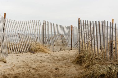 Salisbury Sahili, Massachusetts - tel ve ahşap çitlerle kaplı kumlu bir kış gününde kumsala giden kumlu bir yol.