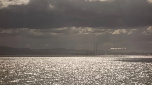 İrlanda 'nın başkenti Dublin' deki Red Rock 'taki kayalıklardan Dublin Körfezi manzarası. Poolbeg güç istasyonunun ikiz kuleleri uzaktan görülebiliyor..