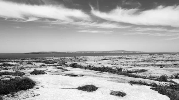 İrlanda 'nın batısındaki Galway' in batı kıyısındaki Aran Adaları 'ndan biri olan İnishmaan (İnis Meain) üzerindeki Karst kireçtaşı manzarası. Inishmore, adaların en büyüğü, uzaklardan görülebilir..