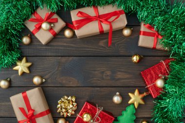 Noel 'in düzlüğü, yeni yıl süslemeleri, kurdelelerden, altın toplardan ve yıldızlardan yorulmuş hediye kutuları ve ahşap arka planda yeşil süslemeler, merkezde kopyalanmış uzay. Tatil kavramı.