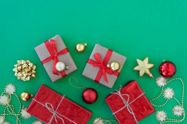 Küçük hediye kutuları kurdele, yeni yıl baloları ve yeşil arka planda altın süslemelerle bezeli. Üst Manzara. Noel ve yeni yıl konsepti. Metin için alanı kopyala