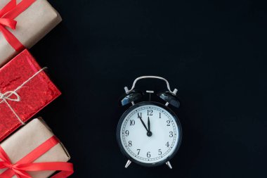 Kara Cuma konsepti. Alarm saatinin üst görüntüsü, siyah arkaplanda kurdeleli üç hediye kutusu, metin için alanı kopyala. Satışlar ve diktatörlük kavramı