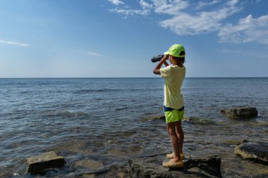 Siyah dürbünlü çocuk deniz kıyısında durur ve önüne bakar. Telif alanı. Aktif yaşam tarzı, deniz maceralarını hayal eder.. 