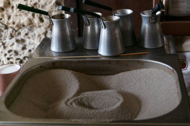 Geleneksel Türk kahvesi hazırlamak için büyük kare çaydanlıkta sıcak kum var.