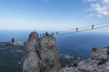 Ukrayna, YALTA - 23 Temmuz 2020: Ai-Petri tepesi, insanlar uzun ip hava köprüsünde yürüyorlar, açık hava faaliyetlerine meydan okuyorlar.