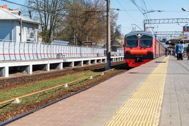 Kırmızı tren, peronun açılması için tren istasyonuna varmak üzere, insanlar biniş için bekliyor. Rahat ve hızlı bir yolculuk.