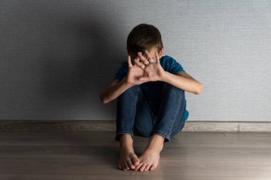 Korkmuş çocuk suistimal durumundan saklanarak kafasını ve yüzünü kapatıyor. Ev içi şiddet, mutsuz çocuklukta duygusal travma..