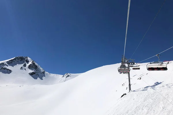 チェアリフト高い雪の山の頂上に人々を持ち上げる アクティブライフスタイルのコンセプト 澄んだ青空 白い雪 スペースのコピー — ストック写真