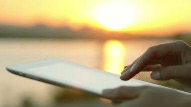 Yakın çekim genç kadın tablet günbatımı üzerinde kullanma