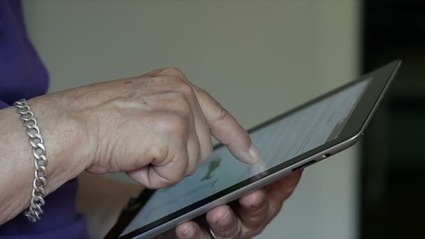 Anciano sostiene en las manos una tableta en casa — Vídeos de Stock