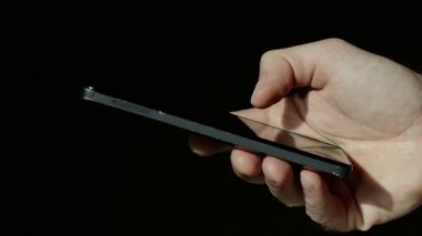 Siyah arka plan üzerine bir akıllı telefon kullanan adamı kapatın