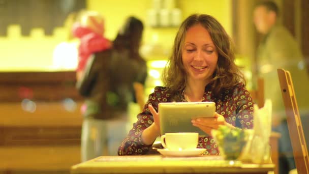 Jóvenes hermosas mujeres usando la tableta en un café — Vídeo de stock