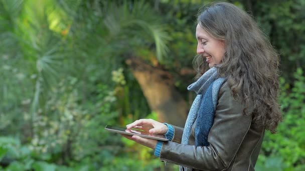 Jeune femme avec une tablette dans le parc — Video