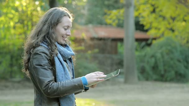 Chica joven con una tableta en el parque — Vídeo de stock