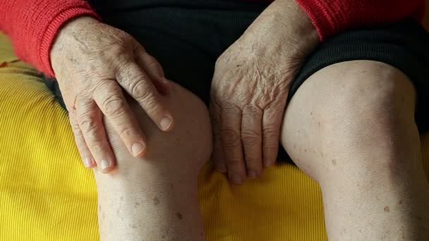 Primer plano de una anciana masajeando su rodilla en el sofá — Vídeos de Stock